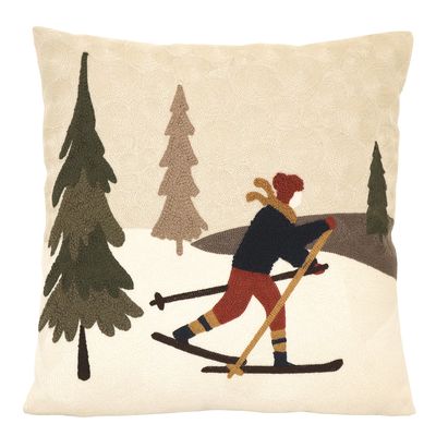 Kuddfodral med vintermotiv som föreställer en skidåkare på tur i ett snötäckt landskap med granar.