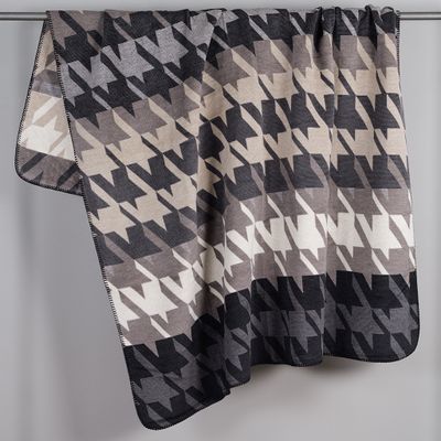 Filt med hundtands mönster hängande över stång.