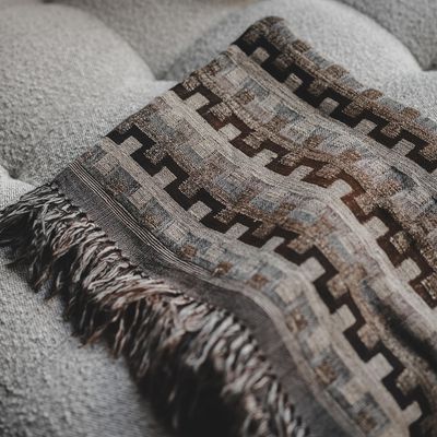 Närbild på Evangeline pläd som visar det grafiska mönstret i naturtoner och dekorativa fransar