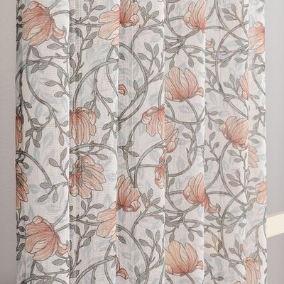 Detaljbild som visar gardinens skira material och slingrande blommönster i gröna och aprikosfärgade nyanser