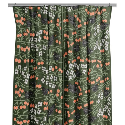 Grön gardin med körsbär, vita blommor och svarta fåglar på tyg, designad av Marianne Westman.
