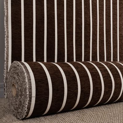 Randigt möbeltyg i mörkbrun ton upprullat på rulle