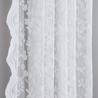 Närbild av offwhite spetsgardin med dekorativ spetskant och blommönster.