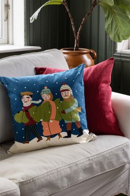 Granen kuddfodral på ljus soffa tillsammans med en röd kudde – julig inredningsdetalj.