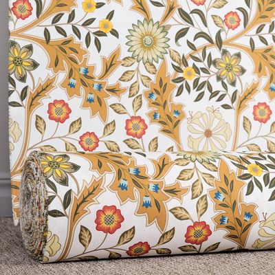 Tyg rullat på rulle med blommönster i varma ockratoner