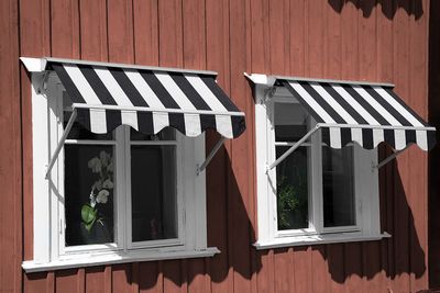 Svart och vit randig markisväv på falurött hus