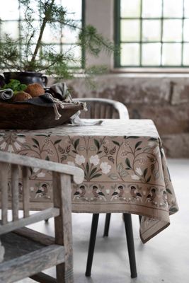 Corinne grön duk med julmönster på beige botten, dukad med granris och dekorativ fågelbård
