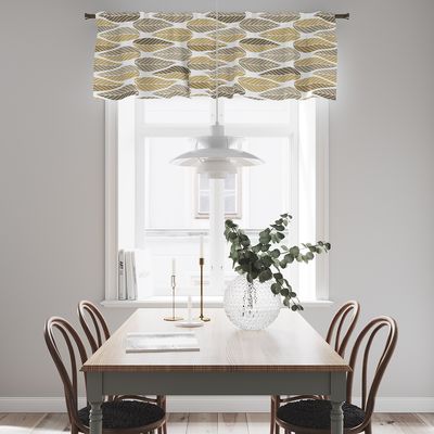 Blader guld gardinkappa med retroinspirerat bladmönster i gult, beige och brunt upphängd över ett ljust fönster vid matplats