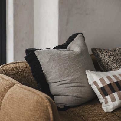 Velora svart kuddfodral i brun soffa tillsammans med mönstrad kudde