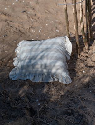 Amalia beige randigt kuddfodral med volang från Fondaco, beigerandigt kuddfodral med volang på sandstrand