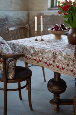 Julefrid röd julduk med beige botten på dukat bord, röda blommor och ekorrar längs kanten