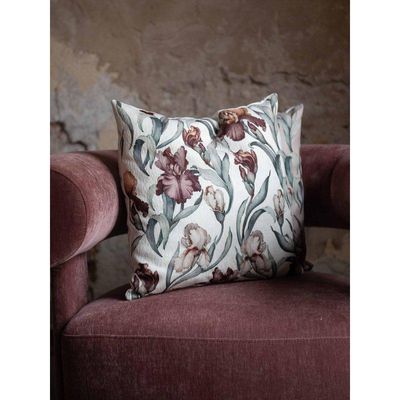 Iris offwhite kuddfodral med irisblommor i vinröda, beige och gröna toner placerat i en rosa fåtölj.