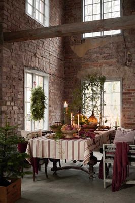 Hedvig beige bordsdduk med röda broderade ränder på ett rustikt juldukat bord med levande ljus och vintergrönt.