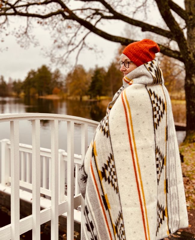 Varm och inbjudande 'Sundborn ullfilt' på en bänk, i klassiska Karin Larsson-färger, väntar på att värma nästa lyckliga ägare.