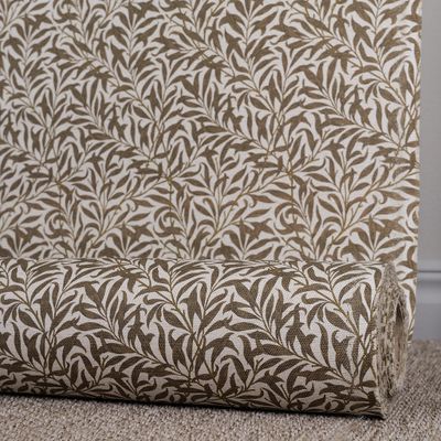 Upprullat tyg med organiskt bladmönster i brunt på greige botten