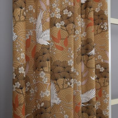 Gardin i färgen bronze med japanskt motiv hängande framför ett fönster, visar mönster och textur.