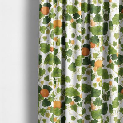 Pumpor gardintyg från Arvidssons Textil upphängt som gardin med orange pumpor och frodiga gröna blad på ljus botten.