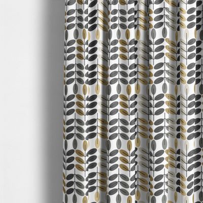 Bladiblad guld gardintyg från Arvidssons Textil upphängt som gardin med grafiskt bladmönster i gula, ockra och grå toner.