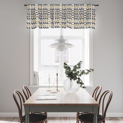 Bladiblad guld gardinkappa med gult och grått bladmönster upphängd vid ett fönster ovanför en matplats.
