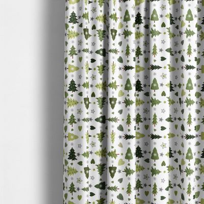 Granåsen vit från Arvidssons Textil upphängt som gardin med grönt julmönster av granar, hjärtan och stjärnor på vit botten.