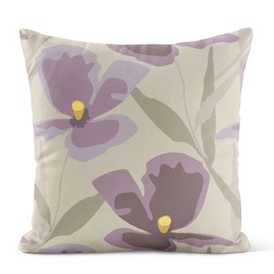 Lila kuddfodral med stora målade blommor i mjuka toner mot ljus botten