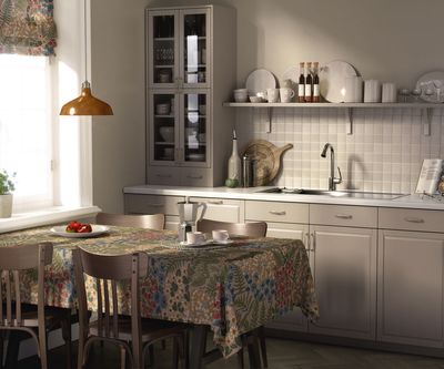Blå blom beige bordsduk på ett matbord i ett ljust kök med matchande hissgardin och ett blomstrande botaniskt mönster.