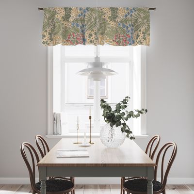 Blå blom beige gardinkappa med blommor och gröna blad upphängd i ett ljust kök med matbord, trästolar och stort fönster.