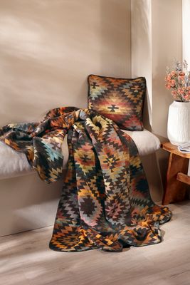 Kudde och pläd med ikatmönster i varm och ombonad miljö