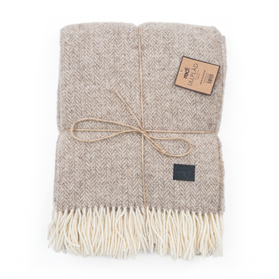 Vacker pläd i 100% ull med vävt mönster i en varm beige nyans.