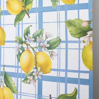 Närbild på vaxduk med citroner, gröna blad och små blommor på blårutigt mönster.