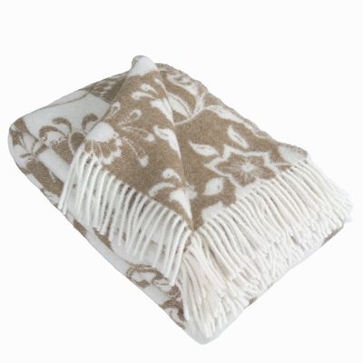 Ullpläd i beige med dalahästar draperad med synliga fransar