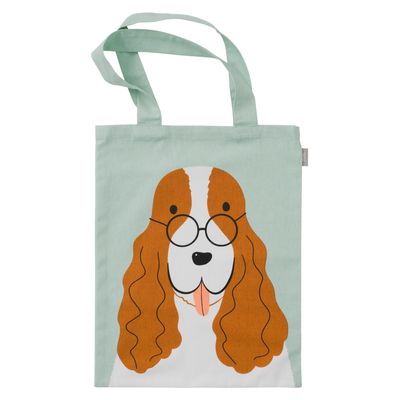 Närbild på tygkasse med illustrerad hund och glasögon mot ljus bakgrund