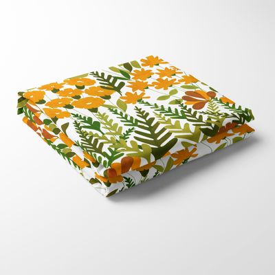 Närbild på Täppan gul bordsduk vikt i rektangel, med färgstarkt mönster av blommor i gult, orange och grönt.