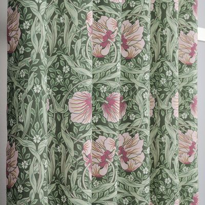 Närbild av gardin med rosa blommor och gröna blad i tätt mönster