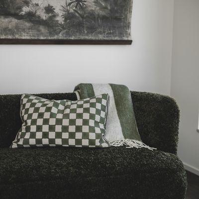 Blocca grön kuddfodral på mörkgrön soffa, närmare miljöbild