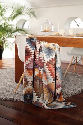 Mönstrad Nomad Light filt draperad över stol i ljus och modern matsalsmiljö