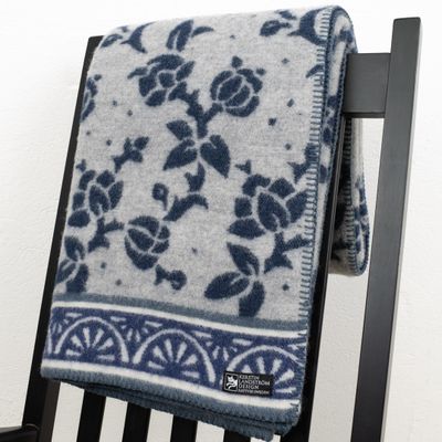 Ullfilt Jugend blå elegant draperad över en fåtölj, med ett mönster inspirerat av jugendstilens rena linjer.