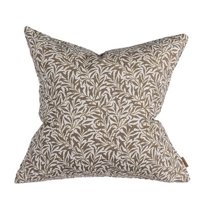 Ramasino kuddfodral i brun ton med dekorativt bladmönster på ljus botten.