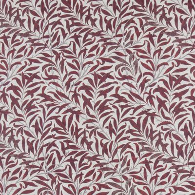 Närbild på textilvaxduken Ester med bladmotiv i vinrött och sand mot ljus linne färgad botten.