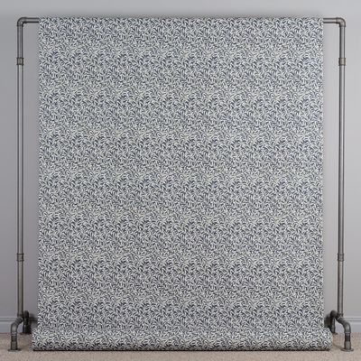 Blått tyg med tätt bladmönster upphängt för att visa mönstrets helhet.