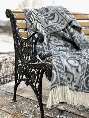 Lyxig HEIDI ullpläd med en blandning av lammull, merinoull och silke, i färgerna mellangrå och naturvit.