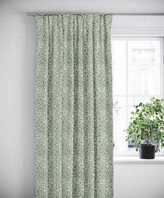 Ester allmogegrön gardin hängande vid ett fönster i ljust skandinaviskt rum med grön växt på fönsterbrädan