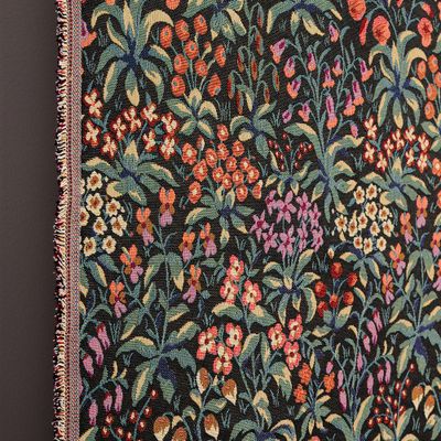 Närbild på Fleurs svart gobeläng som visar vävd struktur och färgstarka blommor mot svart