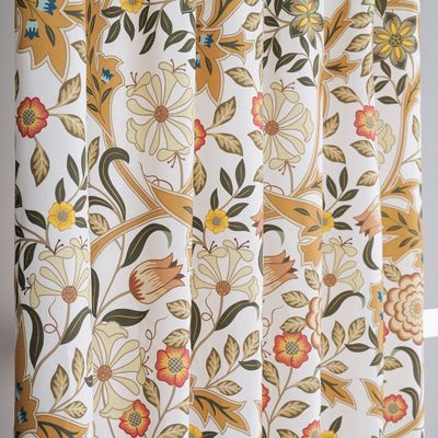 Detalj av gardintyg med blommönster i ockra, grönt och ljusa toner