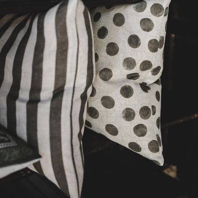 Grönt prickigt kuddfodral tillsammans med randigt kuddfodral i soffa.