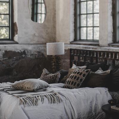 Angelina kuddfodral med grafiskt mönster i jordnära toner placerat på säng tillsammans med matchande textilier