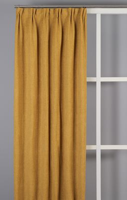 Ockragul mörkläggningsgardin i varm gyllene ton monterad i fönster.