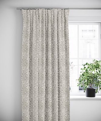 Gardin i Ester beige tyg upphängd framför ett fönster med vit karm och grön växt
