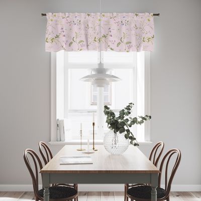 Rosa gardinkappa med blommönster upphängd i ett ljust kök ovanför ett fönster med matbord och stolar