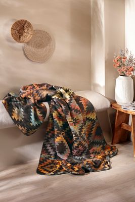 Dekorativ filt med etnomönster i ett varmt och ombonat rum.